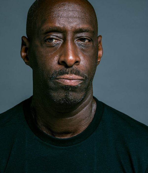 Man in a focused power stance in a dark, minimalist setting.